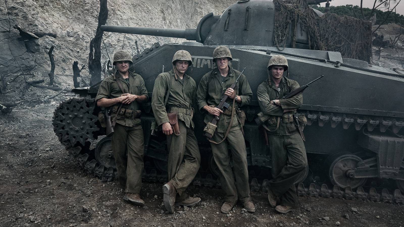 Four World War II soldiers in front of a tank.