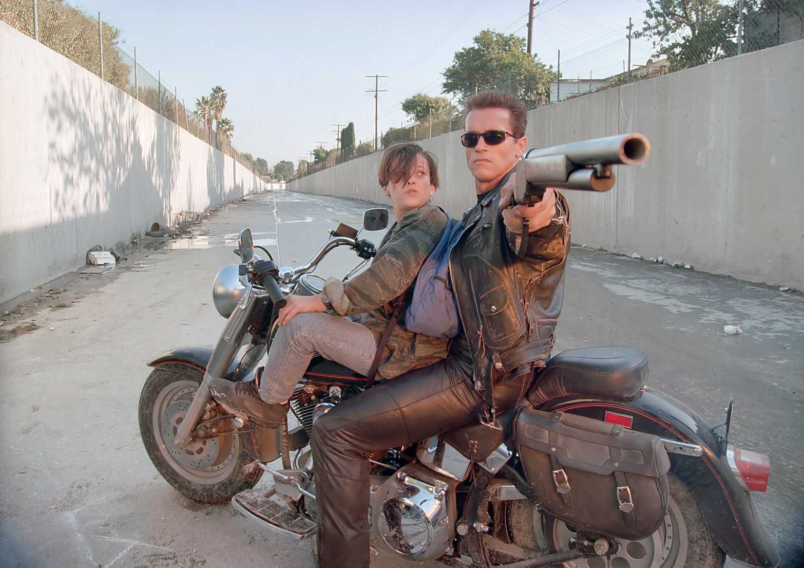 The Terminator points a gun as a young John watches in Terminator 2