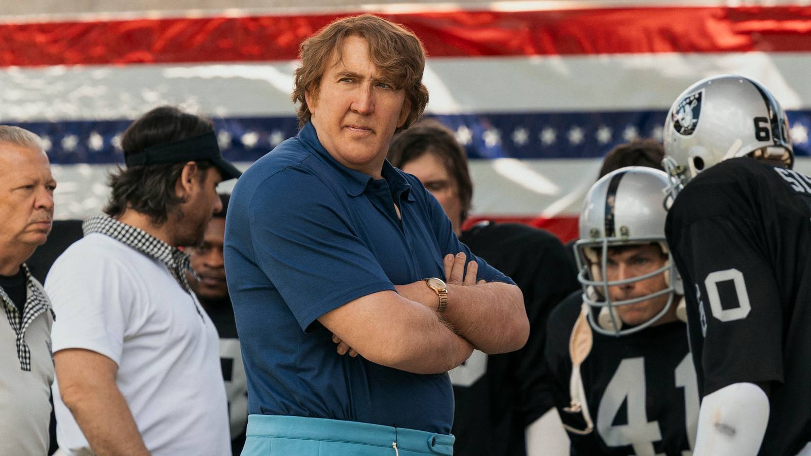 Nic Cage crossing his arm while on the sidelines as John Madden.