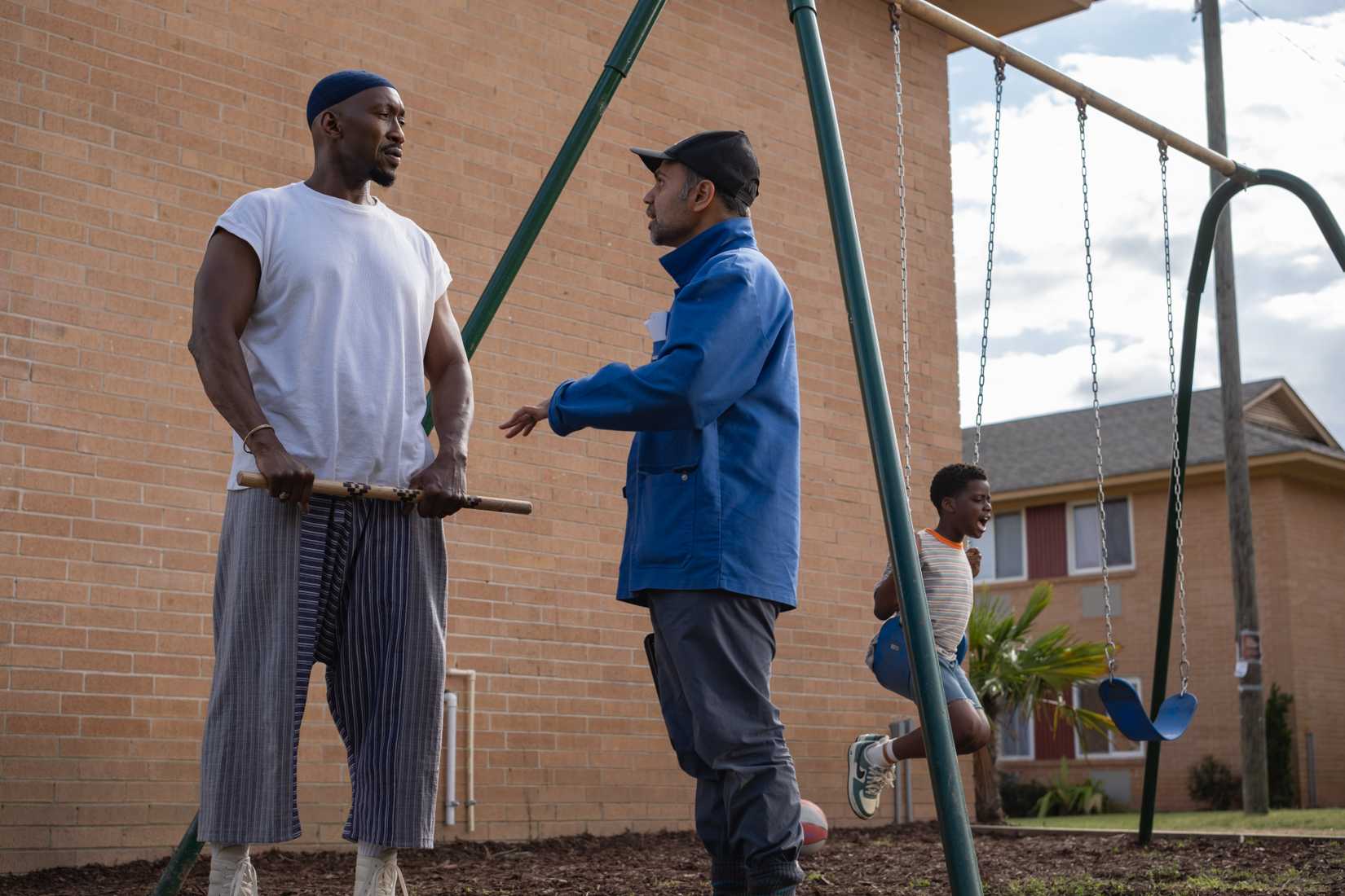 Bassam Tariq and Mahershala Ali on the set of YMYMYM at a playground where Ali is wielding a blade