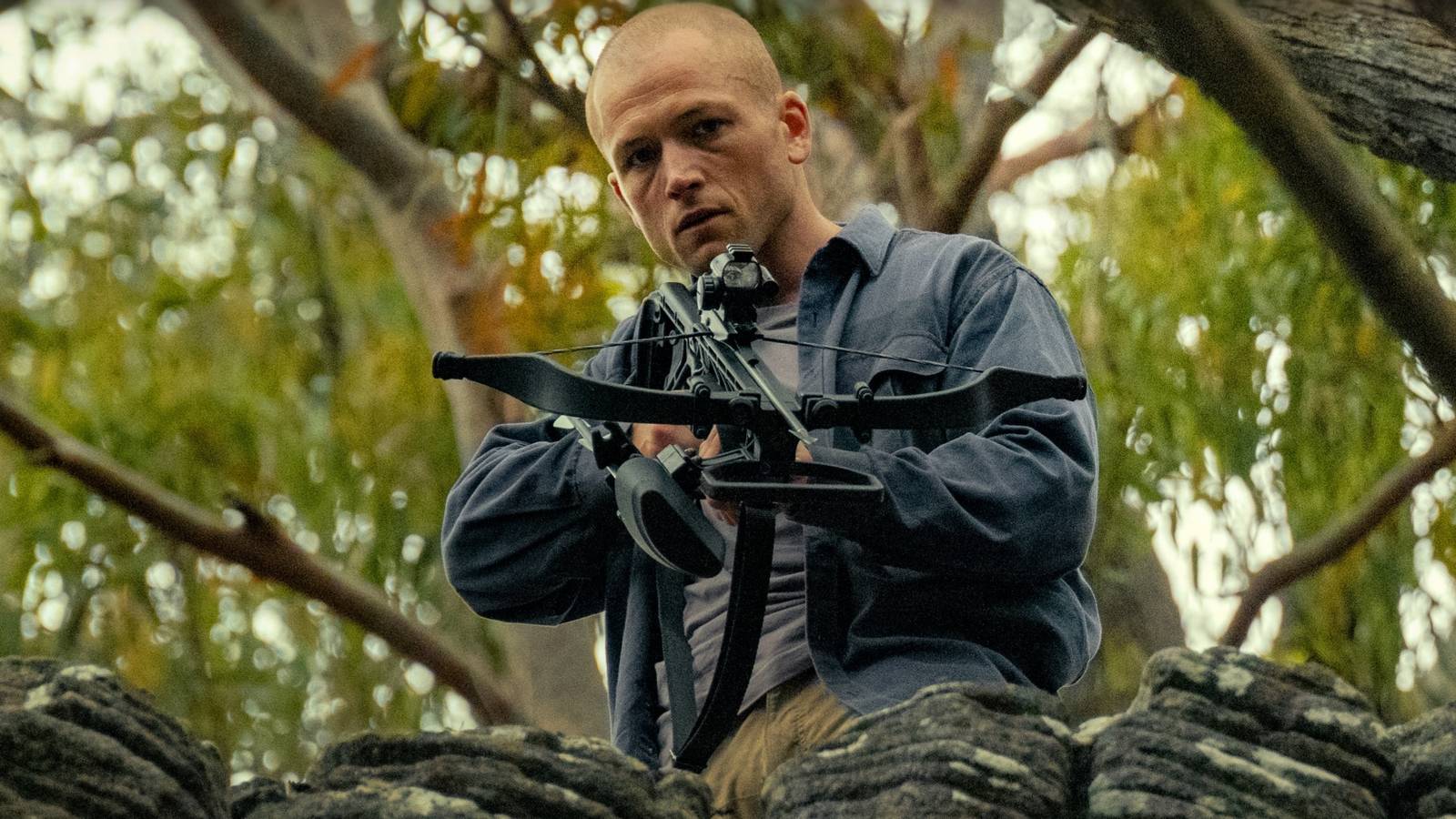 An intimidating bald man played by Joel Edgerton aiming a crossbow