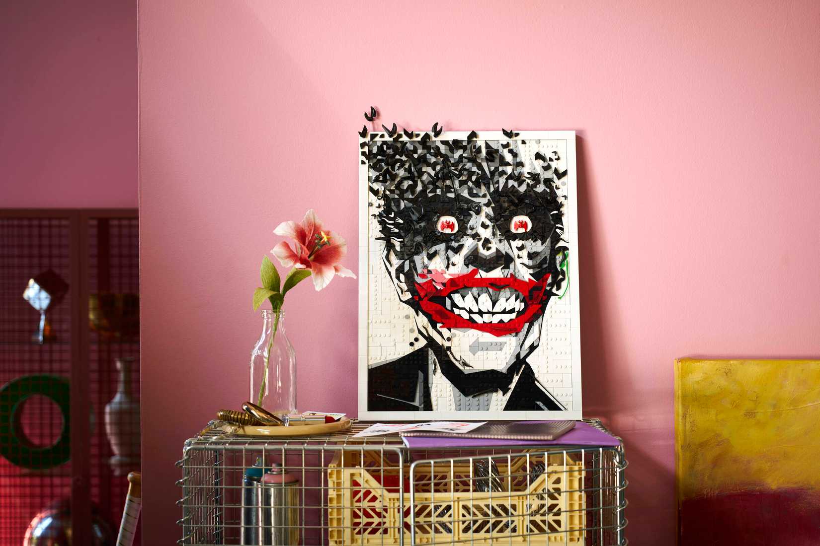 A Lego wall art of a smiling Joker that is black and white with red accents on his face and eyes.