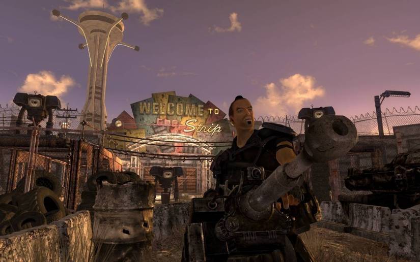 A armed man standing beneath the Welcome to the Strip sign in Fallout: New Vegas