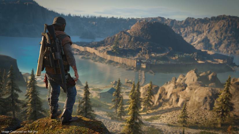 Days Gone hero Deacon St. John overlooks a settlement on the island inside Crater Lake, Oregon.