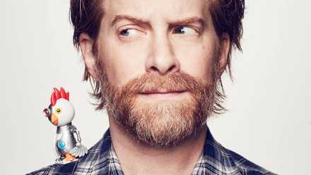the robot chicken from robot chicken sits on the right shoulder of seth green, who is wary