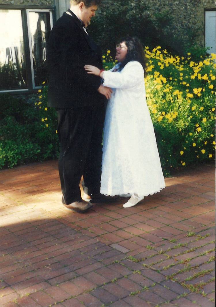 Silas Warner, a tall man in a black tuxedo, with Kari Ann Owen, a shorter woman in a white dress, on their wedding day
