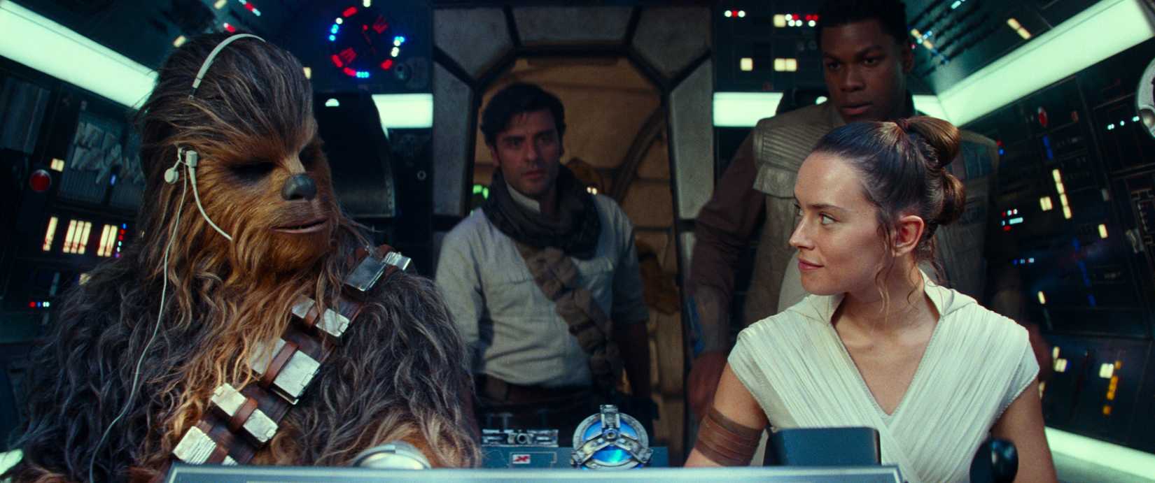 Star Wars: The Rise of Skywalker characters Chewbacca, Poe, Rey, and Finn look at each other in the Millennium Falcon.