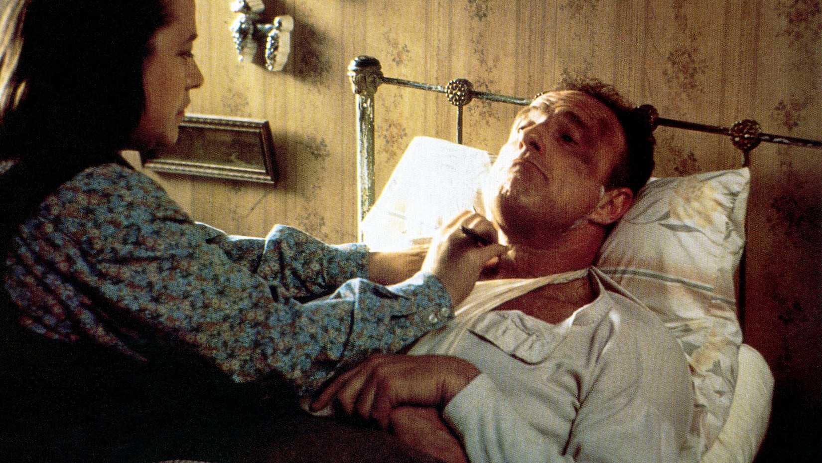 Annie Wilkes shaves a bruised, bandaged, bedridden Paul Sheldon in Misery.