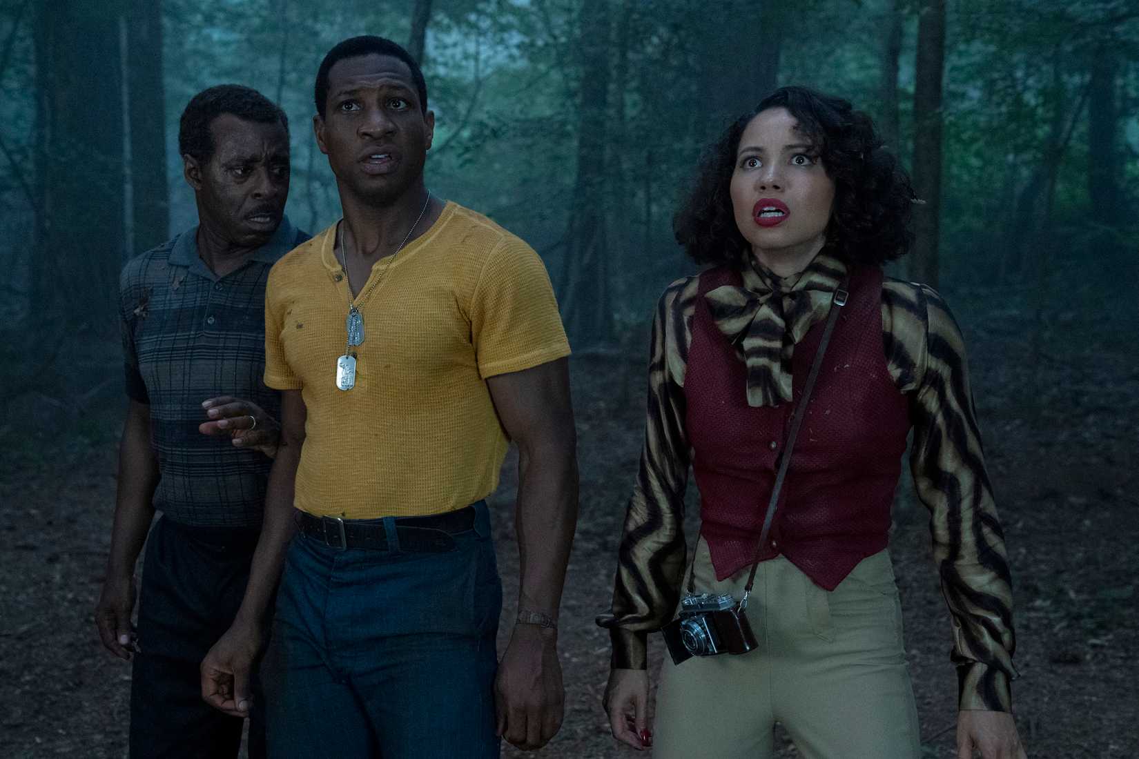 Lovecraft Country’s Courtney B. Vance, Jonathan Majors, and Jurnee Smollett stand in a forest at night, looking with concern at something offscreen.
