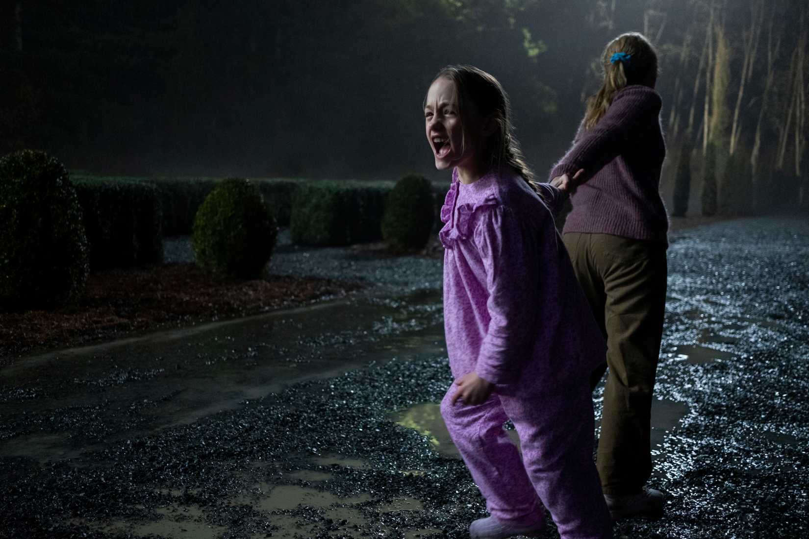 One girl pulls another screaming girl through a big manor garden in The Haunting of Bly Manor