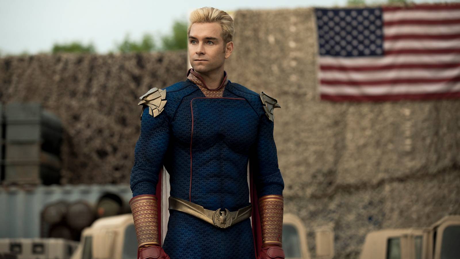 Homelander stands in front of an American flag in a scene from The Boys.