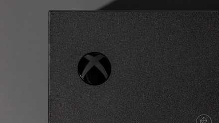 close-up of the Xbox power button on an Xbox Series X video game console photographed on a dark gray background