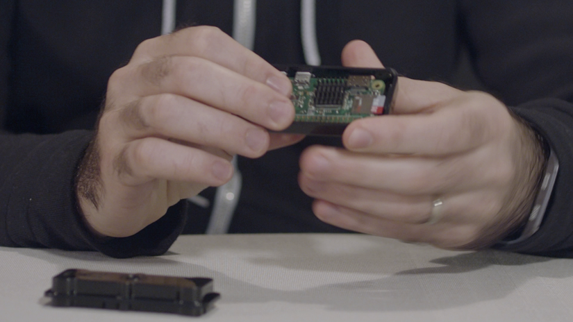 close up of two hands reassembling a small casing around a circuit board