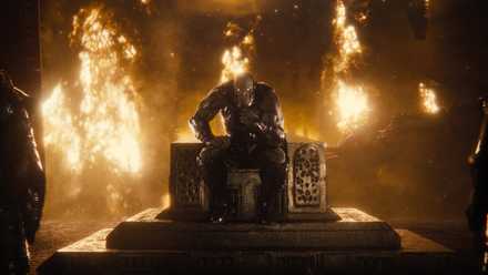 The alien villain Darkseid sits on a throne in a burning room in Zack Snyder’s Justice League