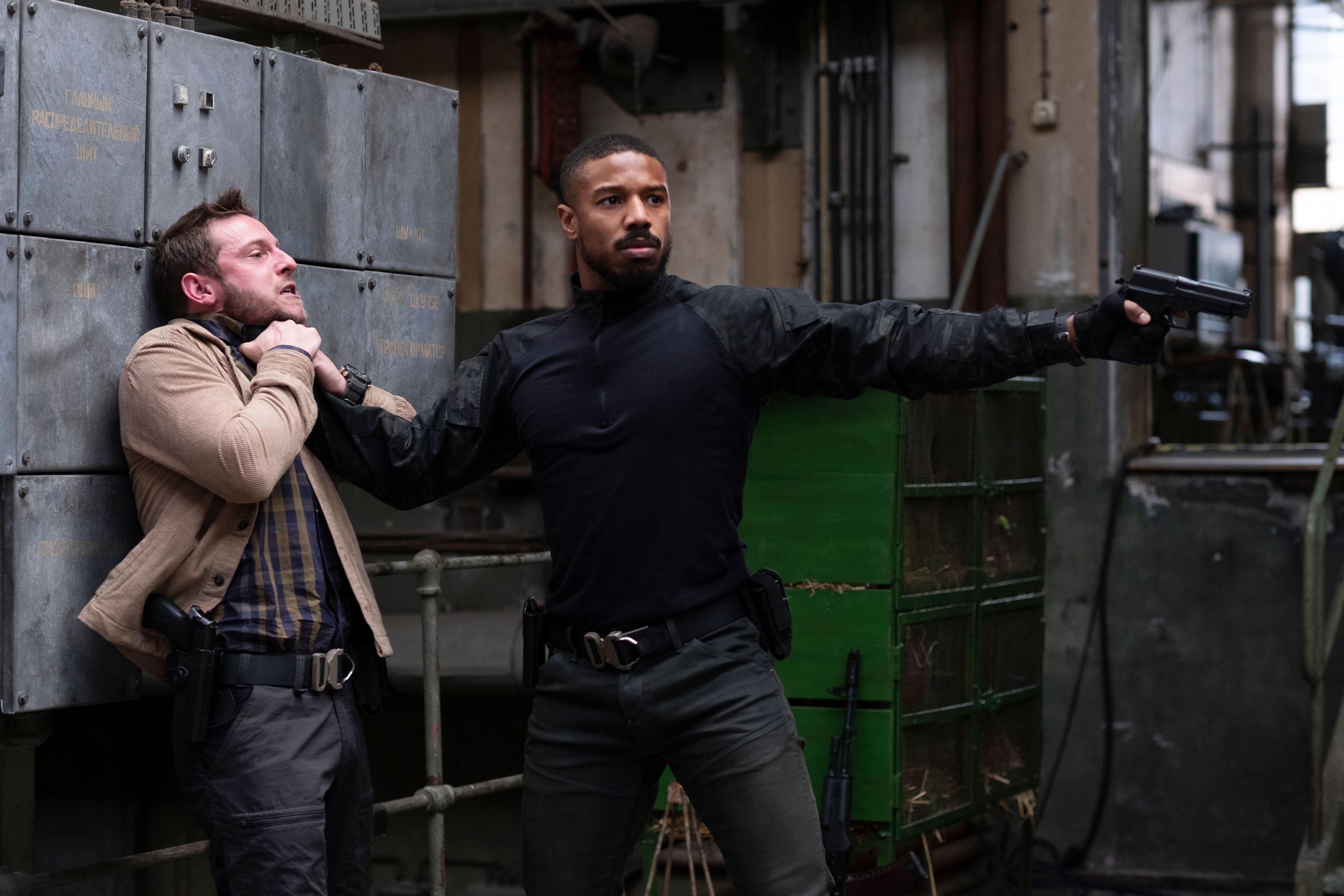 Michael B. Jordan as Navy SEAL John Clark pins a man to a wall by the throat with one hand and points a handgun with the other in Without Remorse