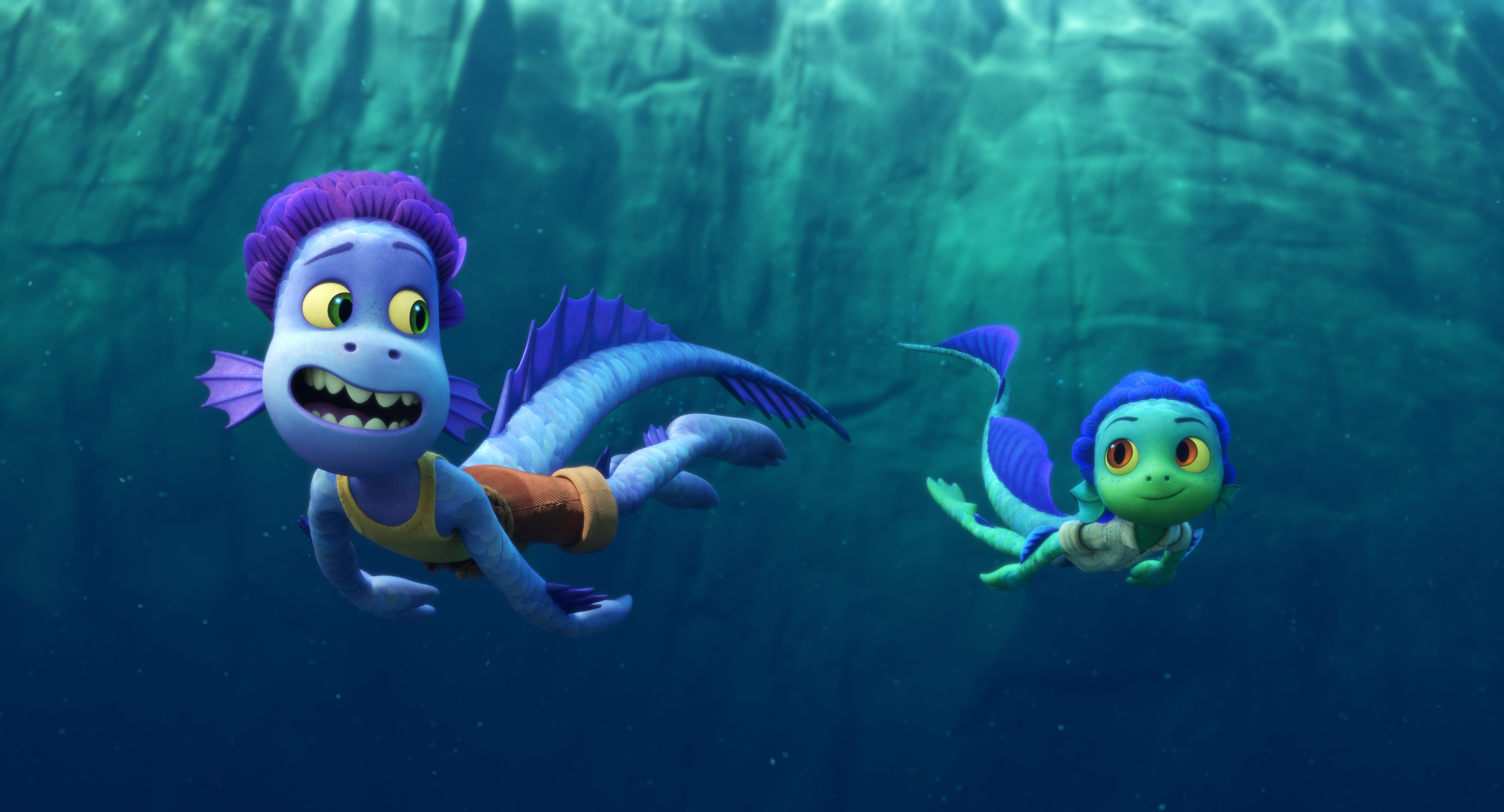 two sea monsters swim in the water. one is blue in color, the one in the back is green. they have scaly skin and fins for ears and long tails