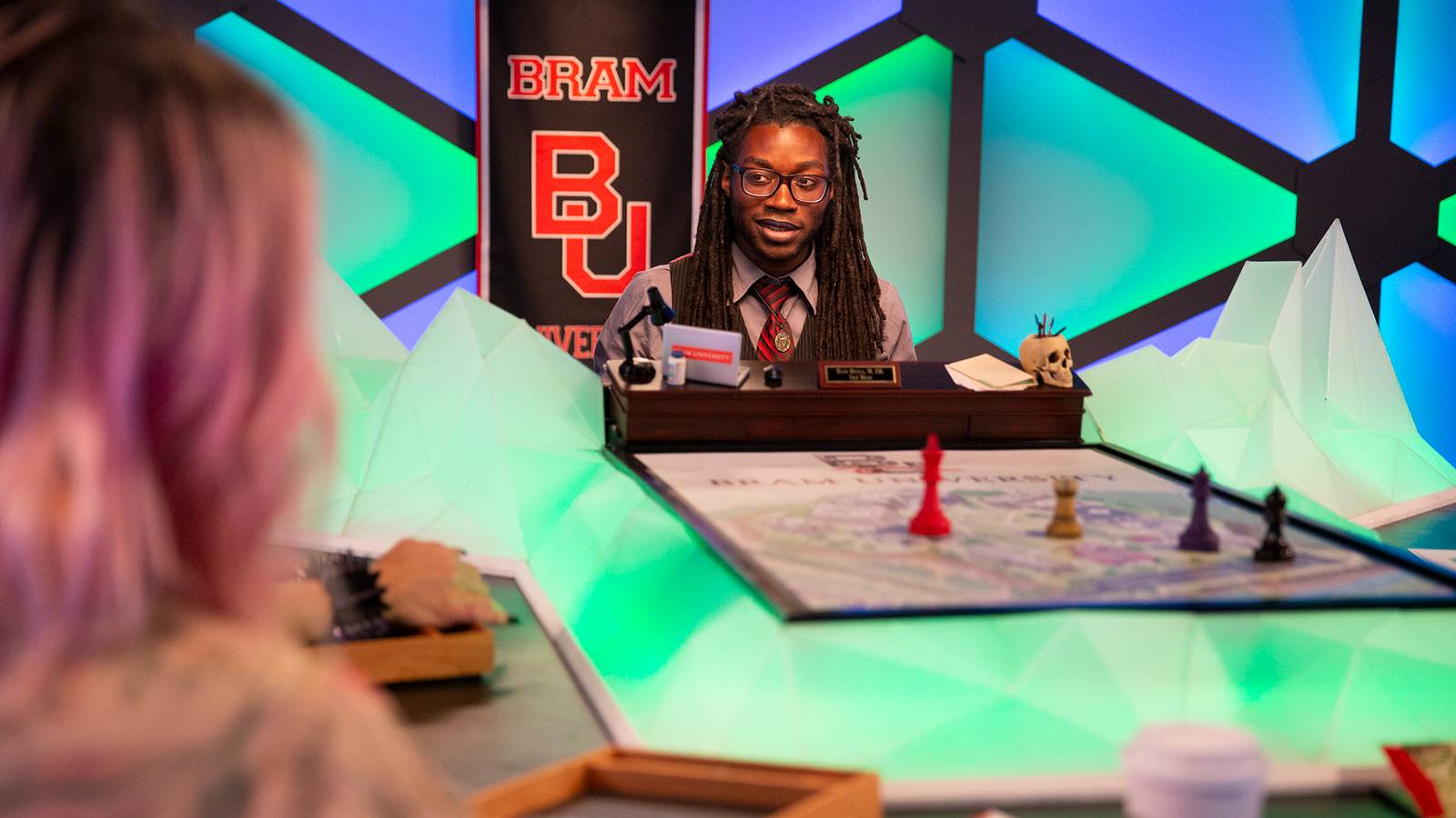 Gabe Hicks at the head of the table, a collegiate banner adorning the wall behind him.