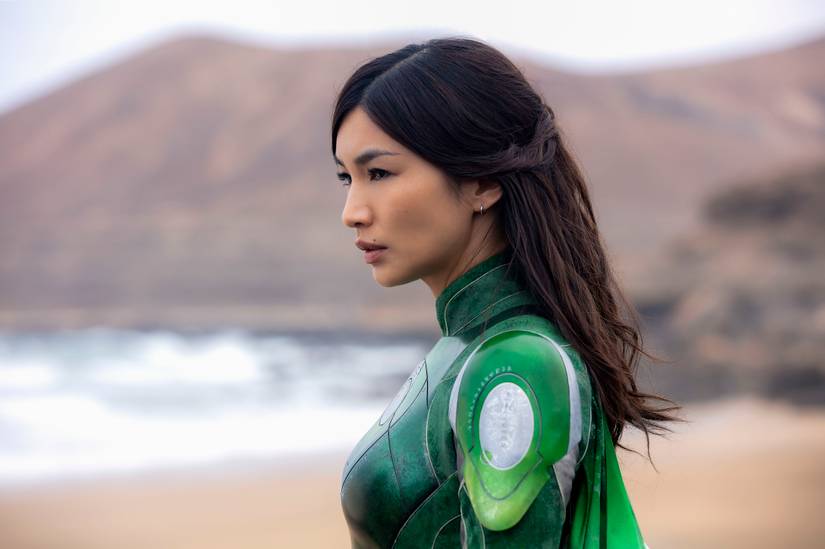Sersi (Gemma Chan) standing in green armor on a beach in Eternals