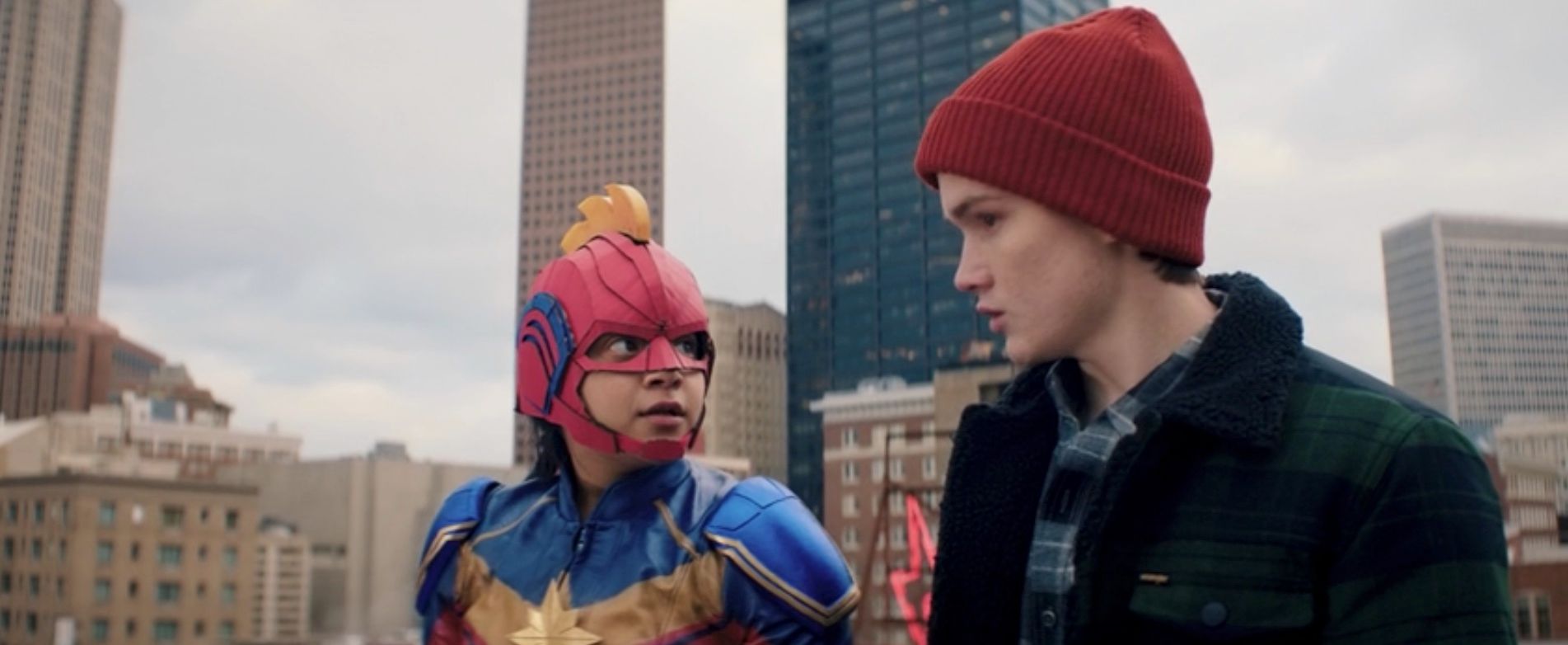 Ms. Marvel and her friend in a red beanie prepare to jump off a building