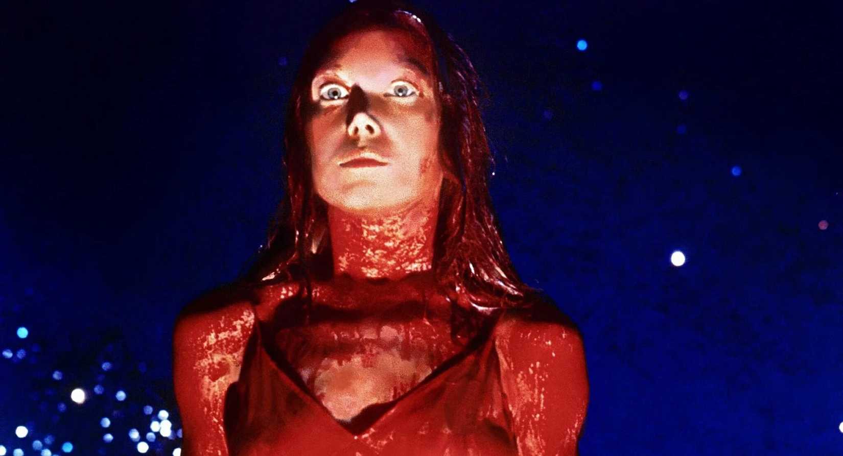 Sissy Spacek as Carrie glaring down in a prom dress coated in pig’s blood in Carrie.