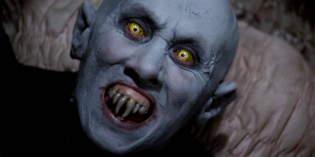 A yellow-eyed vampire with pale skin baring his fangs in Salem’s Lot (1979).