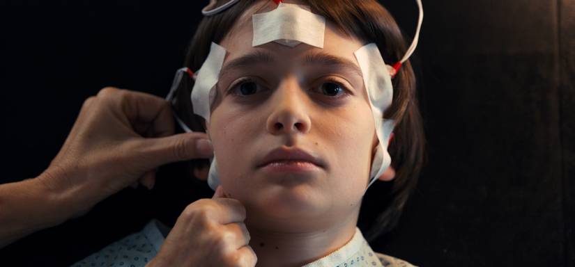 Will lies back as someone attaches wires to his head for an EEG test in Stranger Things