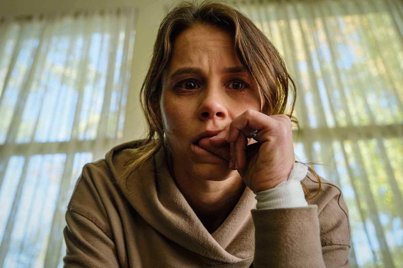 Sosie Bacon as Rose in Smile biting her finger as she contemplates her haunting