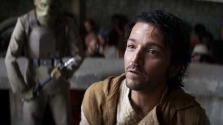 Diego Luna as Cassian Andor pretending to be Keef Girgo, wearing a tan vest as he pleads at the court bench, while a gre