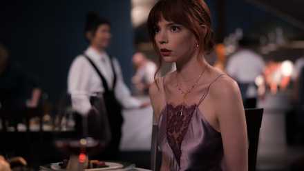 Margo (Anya Taylor-Joy), a young woman in a sheer spaghetti-strap dress, stares at something offscreen with a horrified expression in The Menu