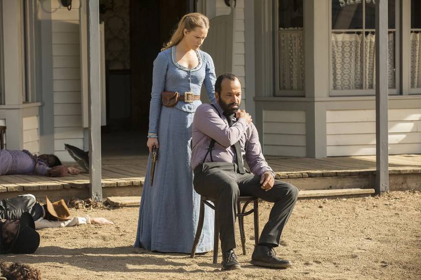 Dolores (Evan Rachel Wood) places her hand on the shoulder of Arnold (Jeffrey Wright) as he sits in front of an old west-style building
