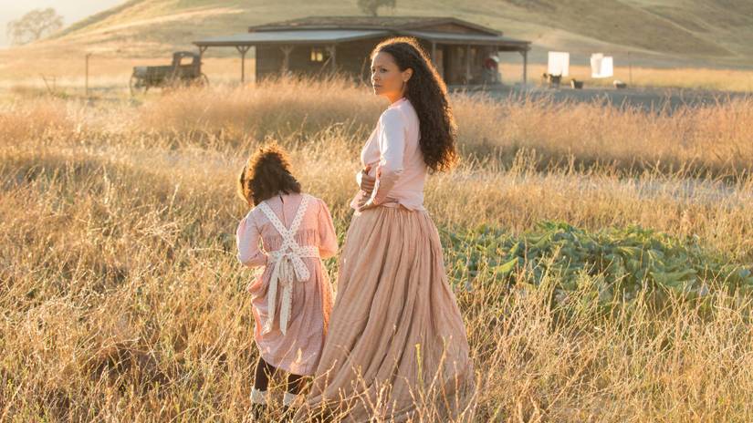 Maeve (Thwandie Newton) and her daughter walk through a field of straw toward a cabin in Westworld season 2