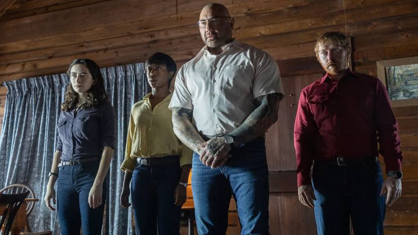 (L-R) Adriane (Abby Quinn), Sabrina (Nikki Amuka-Bird), Leonard (Dave Bautista), and Redmond (Rupert Grint) standing side-by-side inside a cabin.
