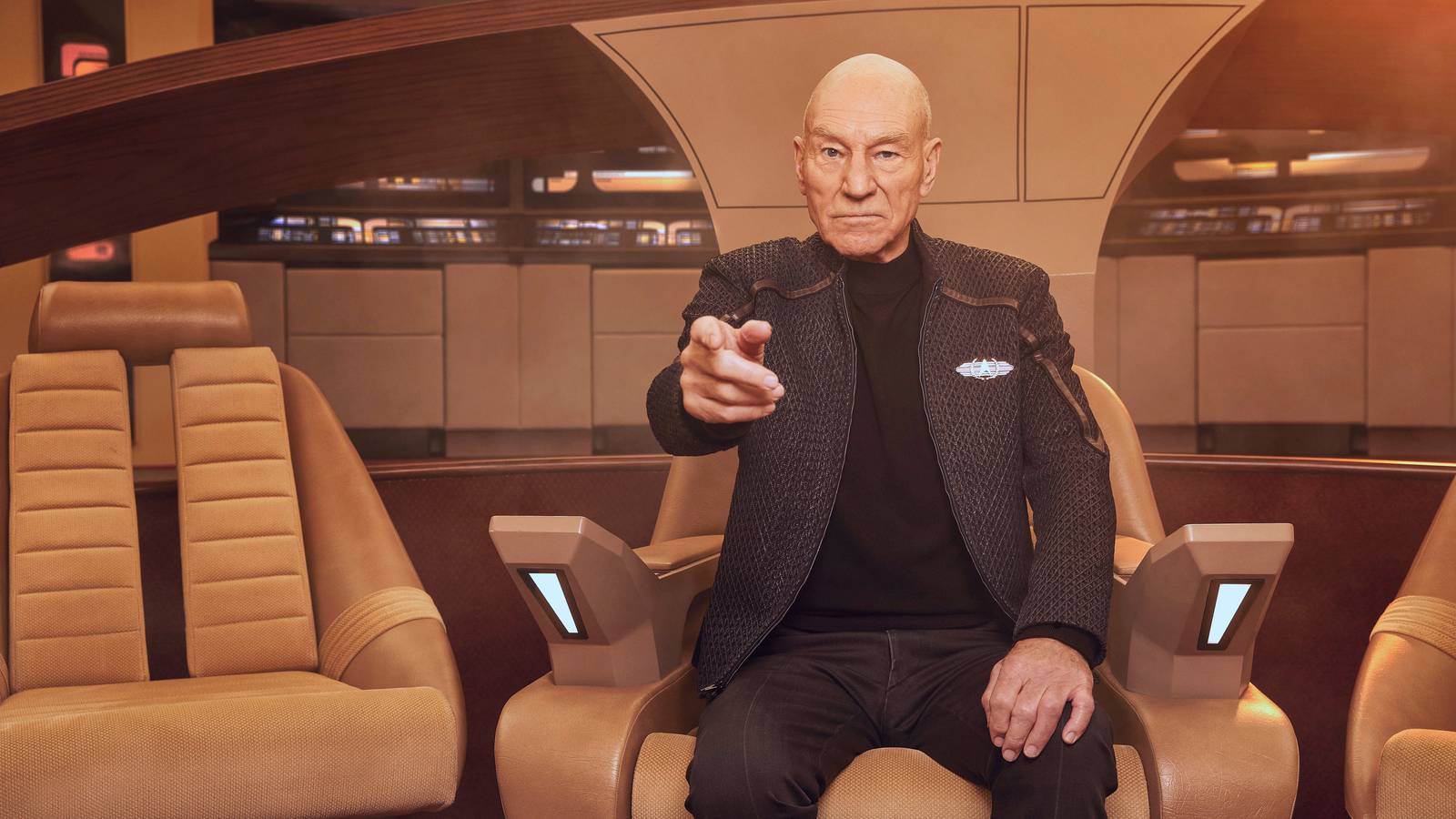 Patrick Stewart as Jean Luc Picard, sitting in his captain’s chair and making his classic “engage” gesture, in Picard.