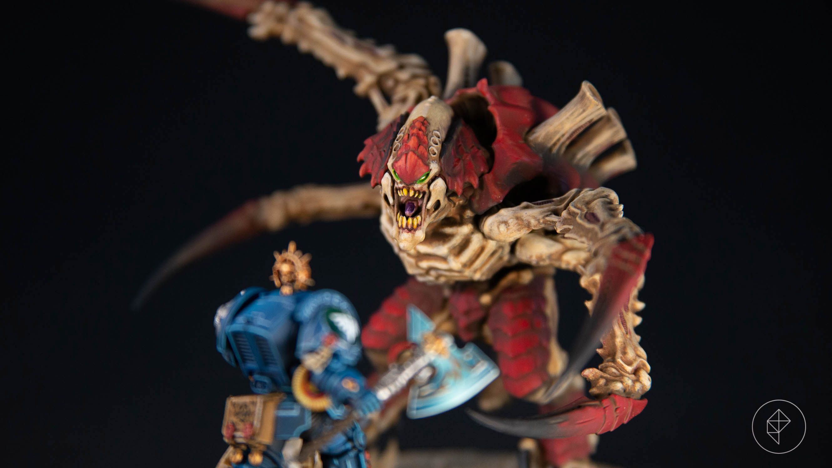 A close-up of a Screamer-Killer Tyrannid against a black background, closing in on a Terminator Librarian Space Marine. The image has a fairly short depth of field.
