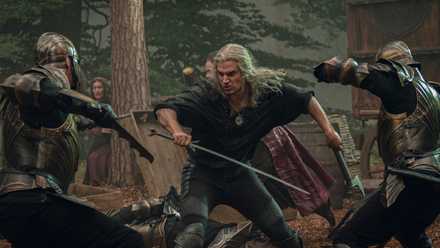 Geralt wields a sword and axe as soldiers attack him on each side in a fight scene from The Witcher season 3