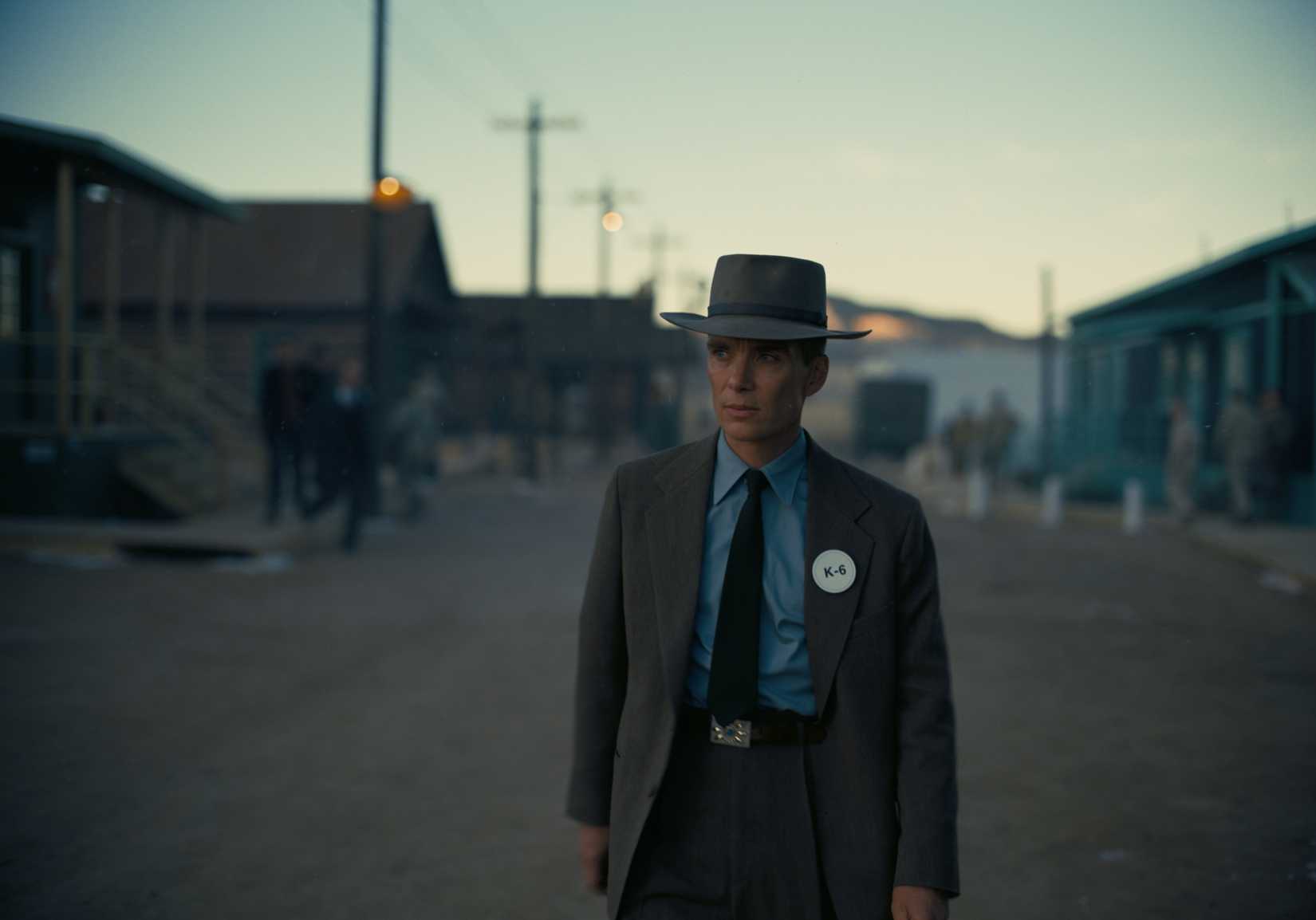 Oppenheimer walks the empty dirt roads of the Manhattan Project in Los Alamos as the sun sets behind him in a scene from Oppenheimer
