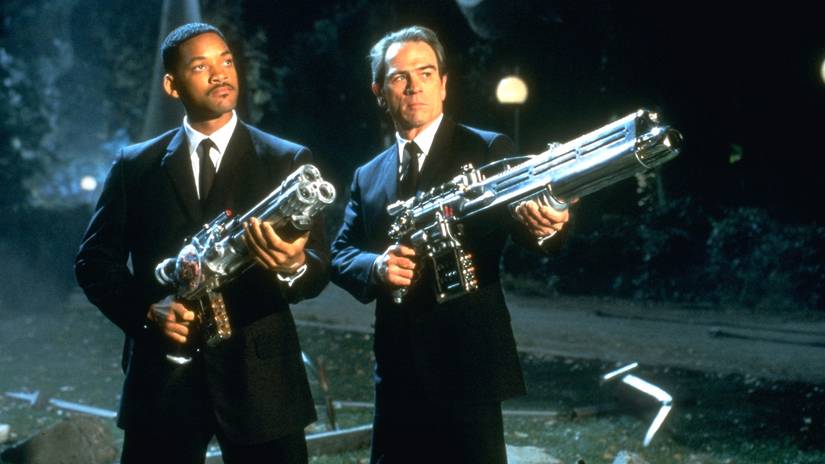 (L-R) Will Smith and Tommy Lee Jones as Agent J and K holding large chrome colored space rifles in Men in Black.