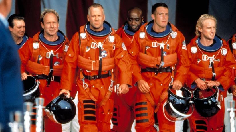(L-R) Steve Buscemi, Will Patton, Bruce Willis, Michael Clarke Duncan, Ben Affleck, and Owen Wilson in orange astronaut uniforms in Armageddon.
