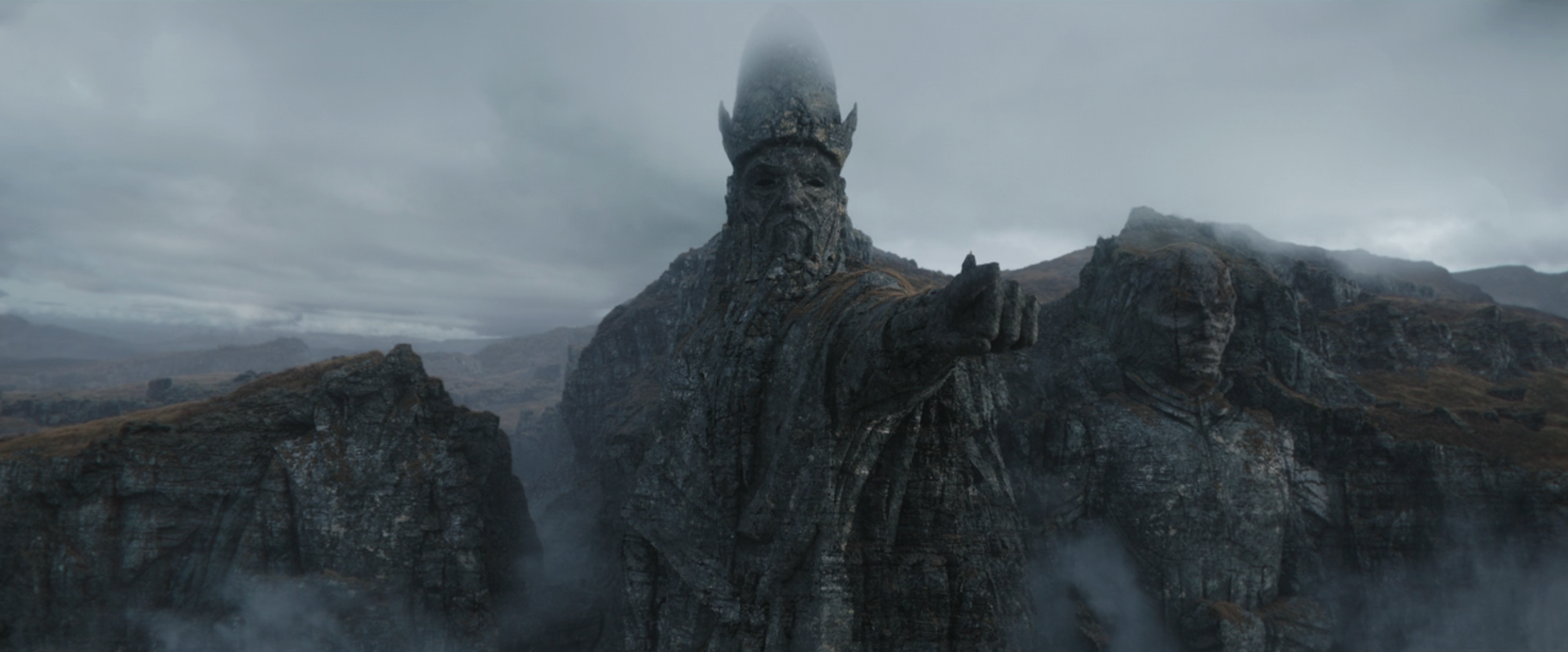 Gaylan stands on the outstreched arm of a massive statue of the Father, carved from a cliffside. On the father’s right is a carving of the Son, and on his left is a crumbled carving of the Daughter, its head gone, in Ahsoka. 