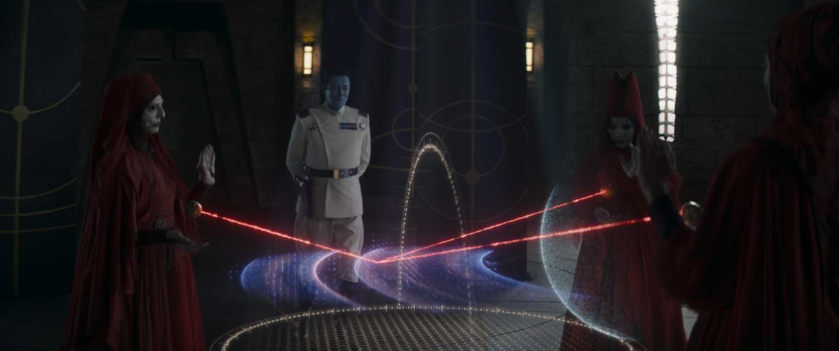 Thrawn stands in front of a display being manipulated by the three red-robed Witches of Dathomir in a scene from the DIsney Plus series Ahsoka