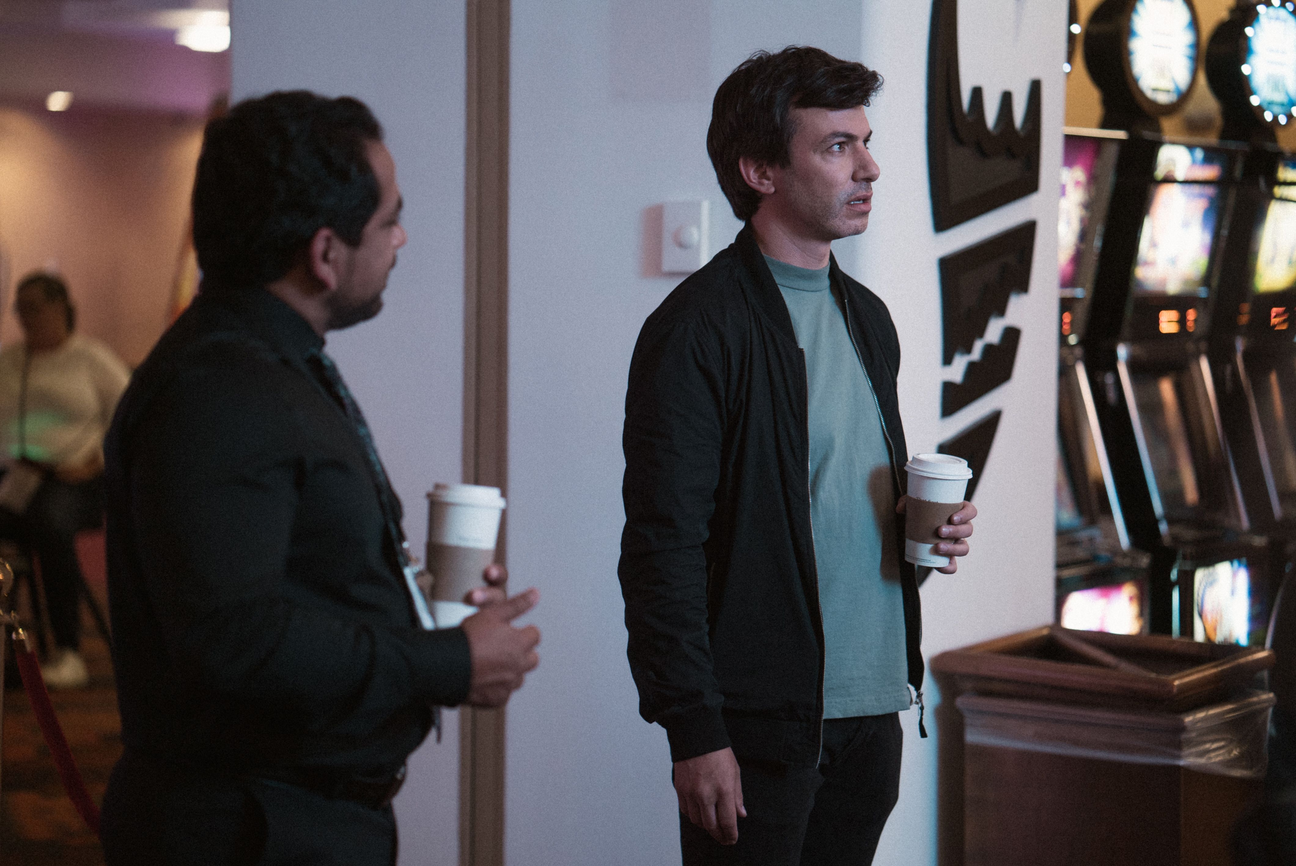Asher (Nathan Fielder) stands looking at something in quiet disbelief while someone talks to him