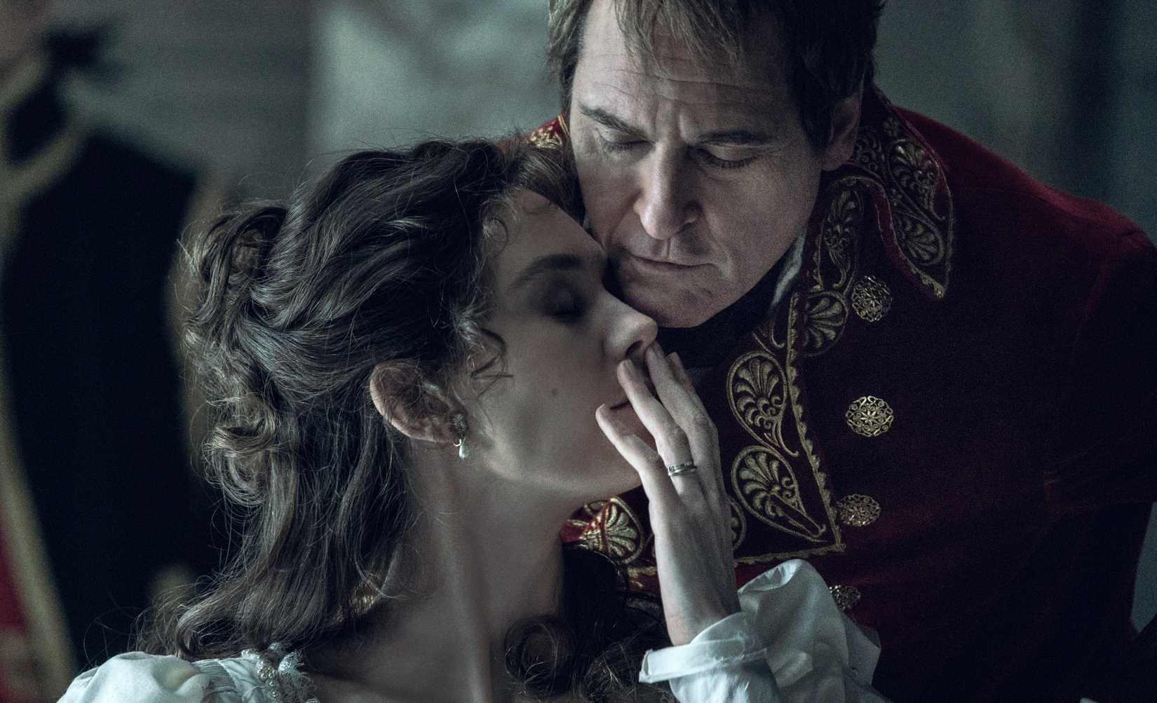 Napoleon Bonaparte leans forward over his wife Josephine’s face, who is turning to the side with her mouth covered by her hand in the film Napoleon.