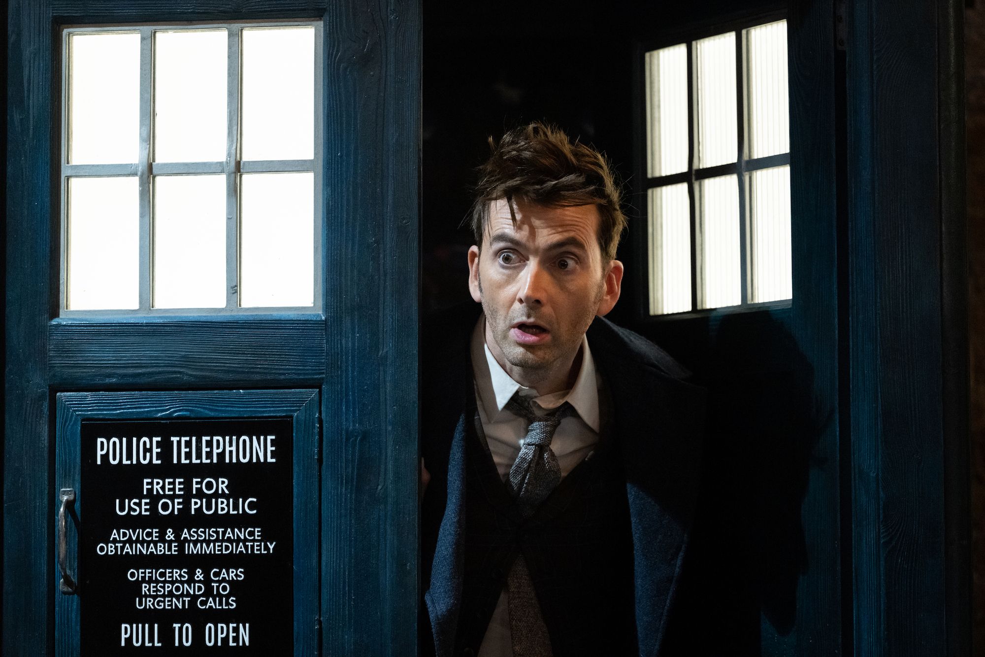 David Tennant’s Fourteenth Doctor peeks out of the blue police box doors of the TARDIS in one of the Doctor Who 60th anniversary specials