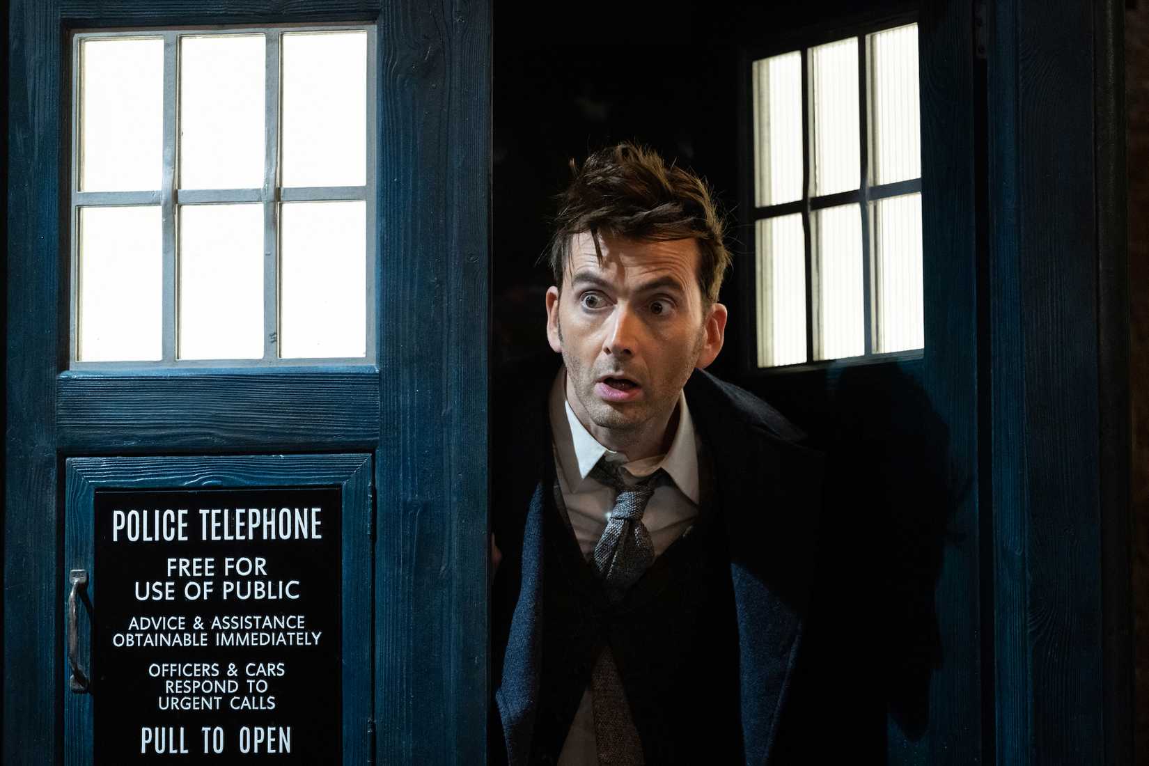 David Tennant’s Fourteenth Doctor peeks out of the blue police box doors of the TARDIS in one of the Doctor Who 60th anniversary specials