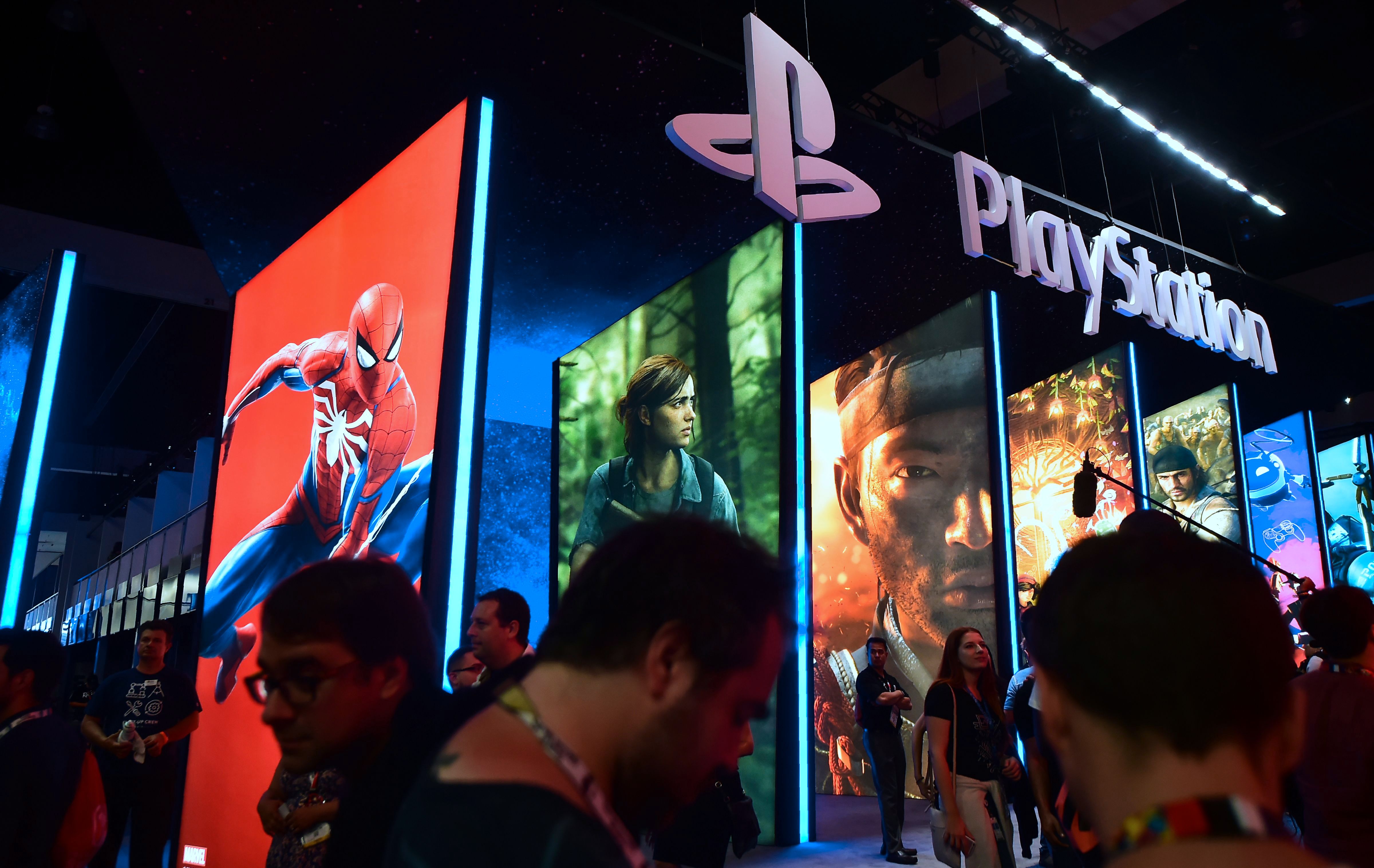 People wander in front of the Playstation posters at the 24th Electronic Expo, or E3 2018, in Los Angeles, California on June 12, 2018, where hardware manufacturers, software developers and the video game industry present their new games. (Photo by Frederic J. BROWN / AFP)