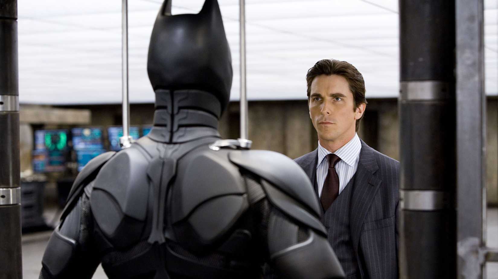 Bruce Wayne đứng đối diện với bộ giáp Batman trong The Dark Knight