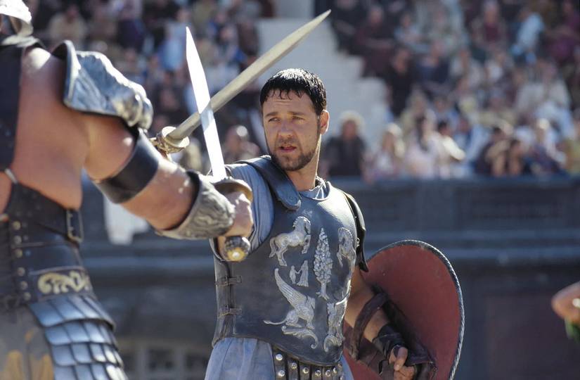 Russell Crowe as General Maximus Decimus Meridius crossing swords with a gladiator in Gladiator.