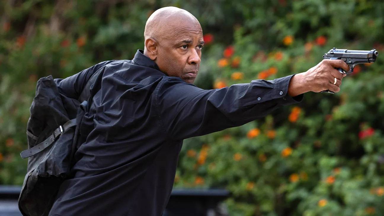 Denzel Washington aiming a pistol and holding a black bag in The Equalizer 3.