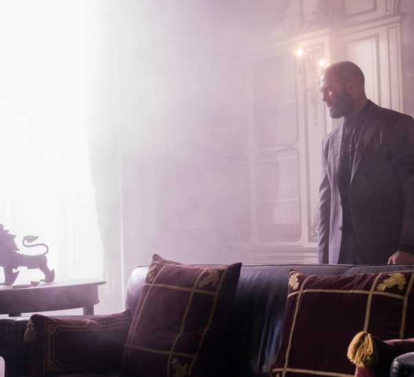 Jason Statham smolders in a brightly lit room with fancy furniture and decorations in The Beekeeper.