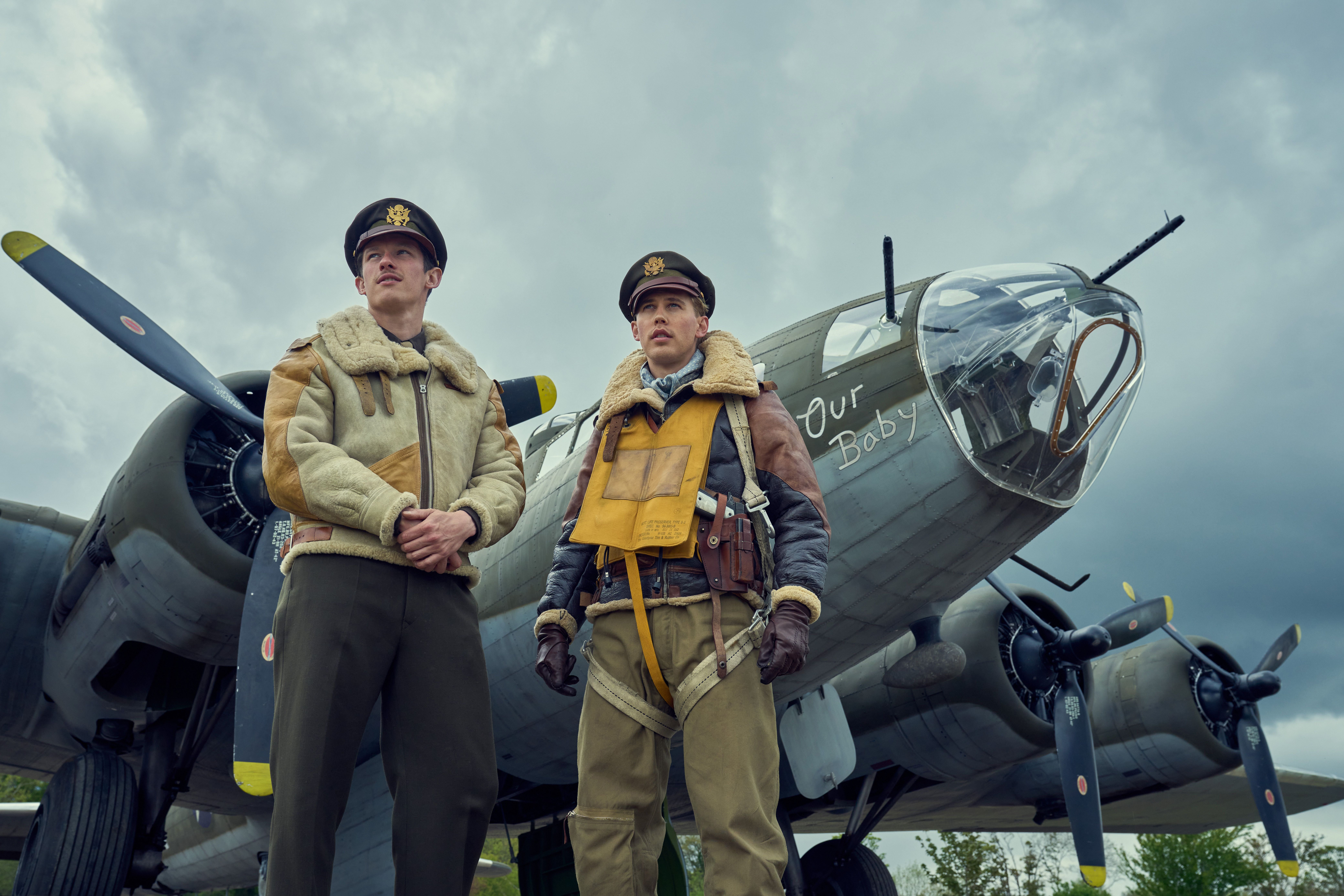 Callum Turner and Austin Butler stand befor Our Baby, one of the many il-fated Fortresses that co-star in Masters of the Air. It’s bristling with guns.